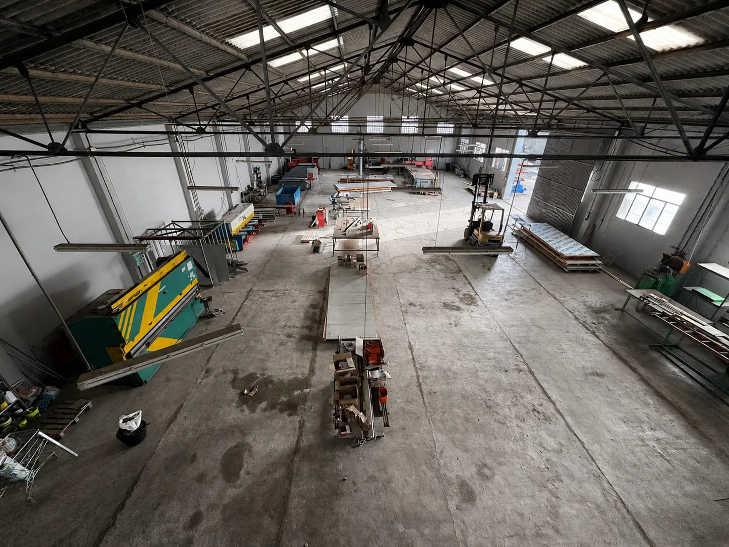 Vista panorámica de la nave de mecanizado del taller de Valencia, con la plegadora, mesas de corte y una carretilla elevadora